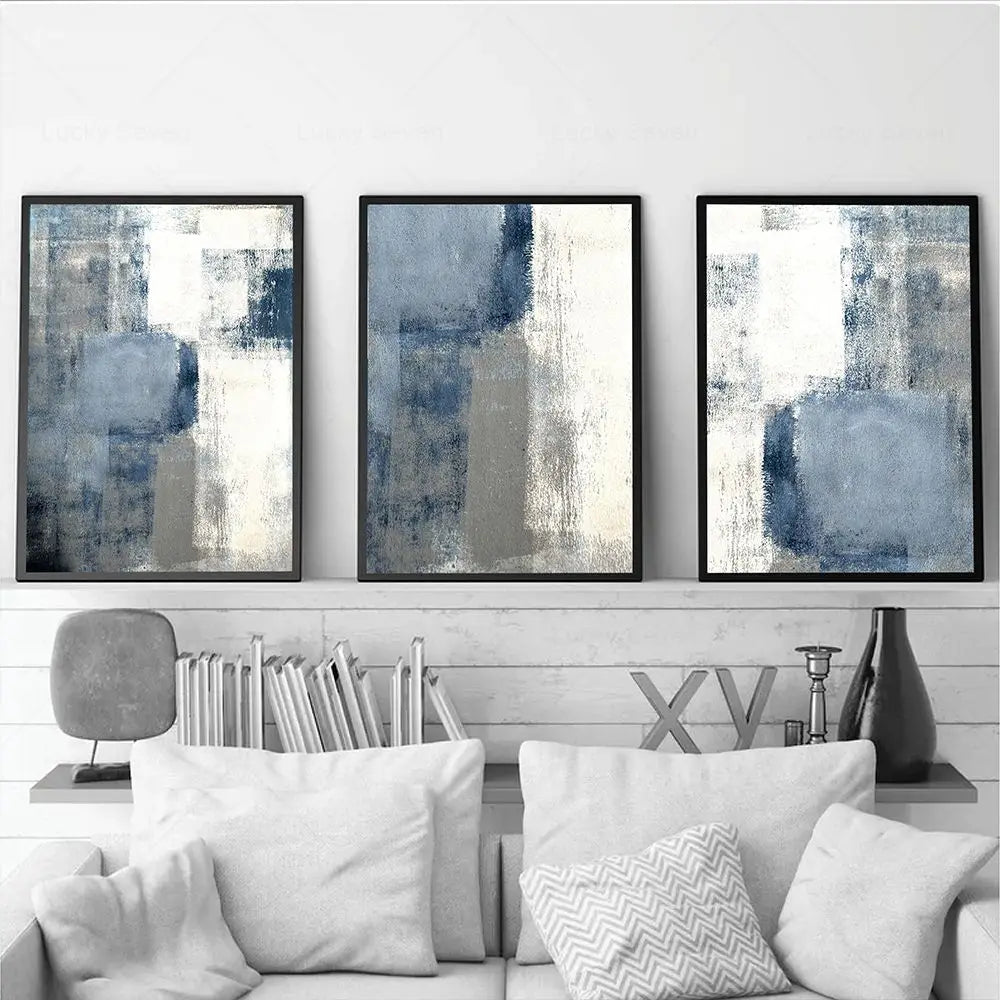 Three abstract art pieces in black frames on a wall above a sofa with decorative pillows.