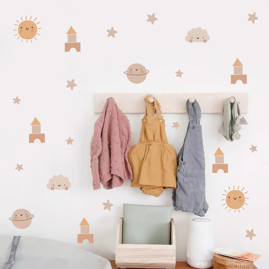 Children's clothing hanging on a hook against a wall with decorative stickers.