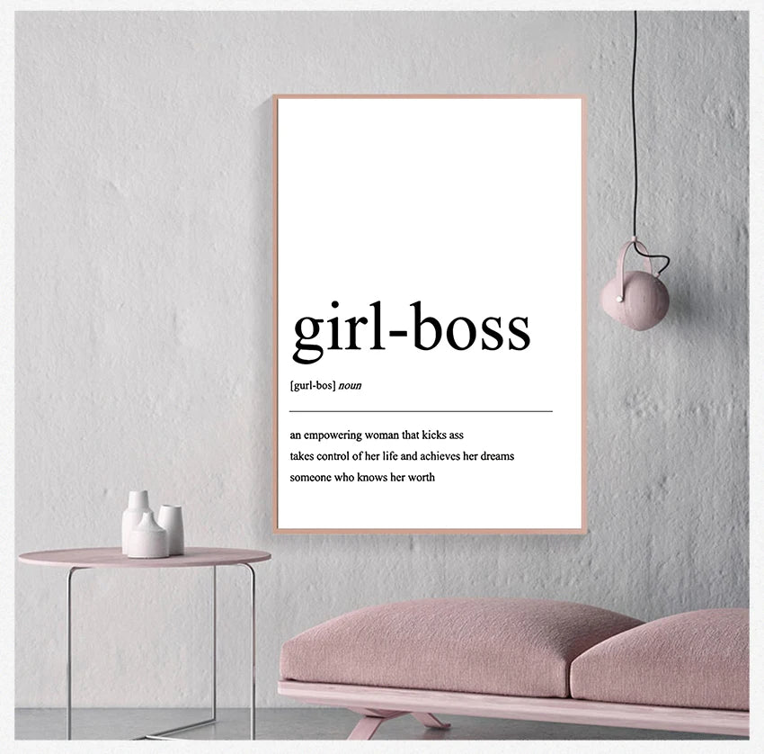 Framed poster with 'girl-boss' definition on a wall in a modern interior setting.