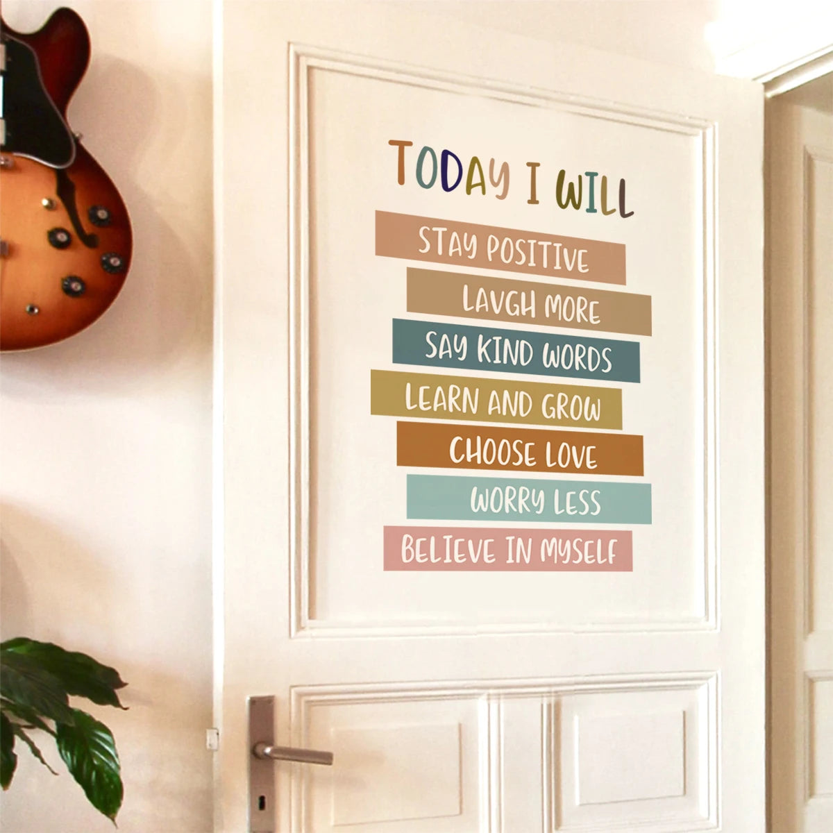 Motivational poster with affirmations on a wall next to a guitar
