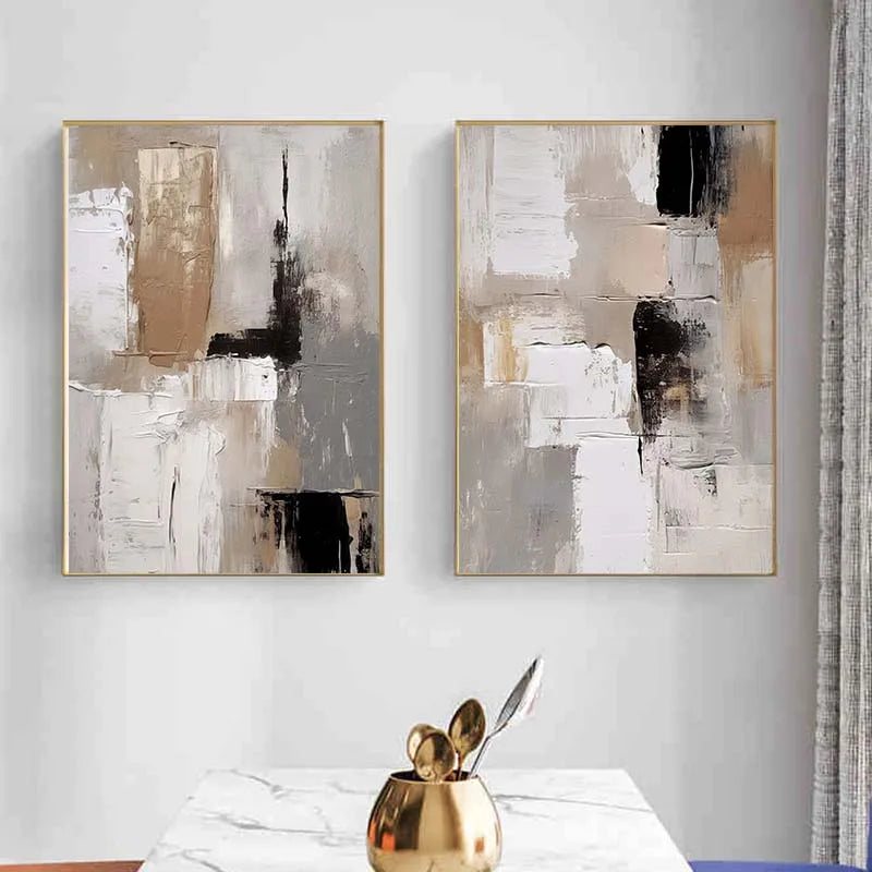 Two abstract art pieces in gold frames on a wall above a table with decorative items.