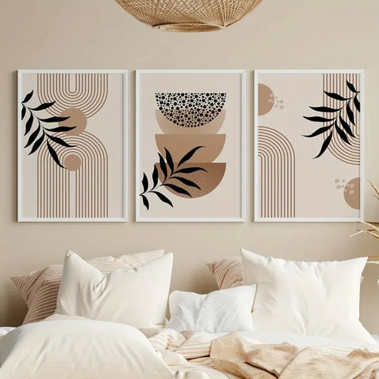 Three abstract wall art prints on a beige wall above a bed with white bedding.
