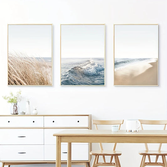 Three framed beach scenes on a wall above a dining table and chairs.
