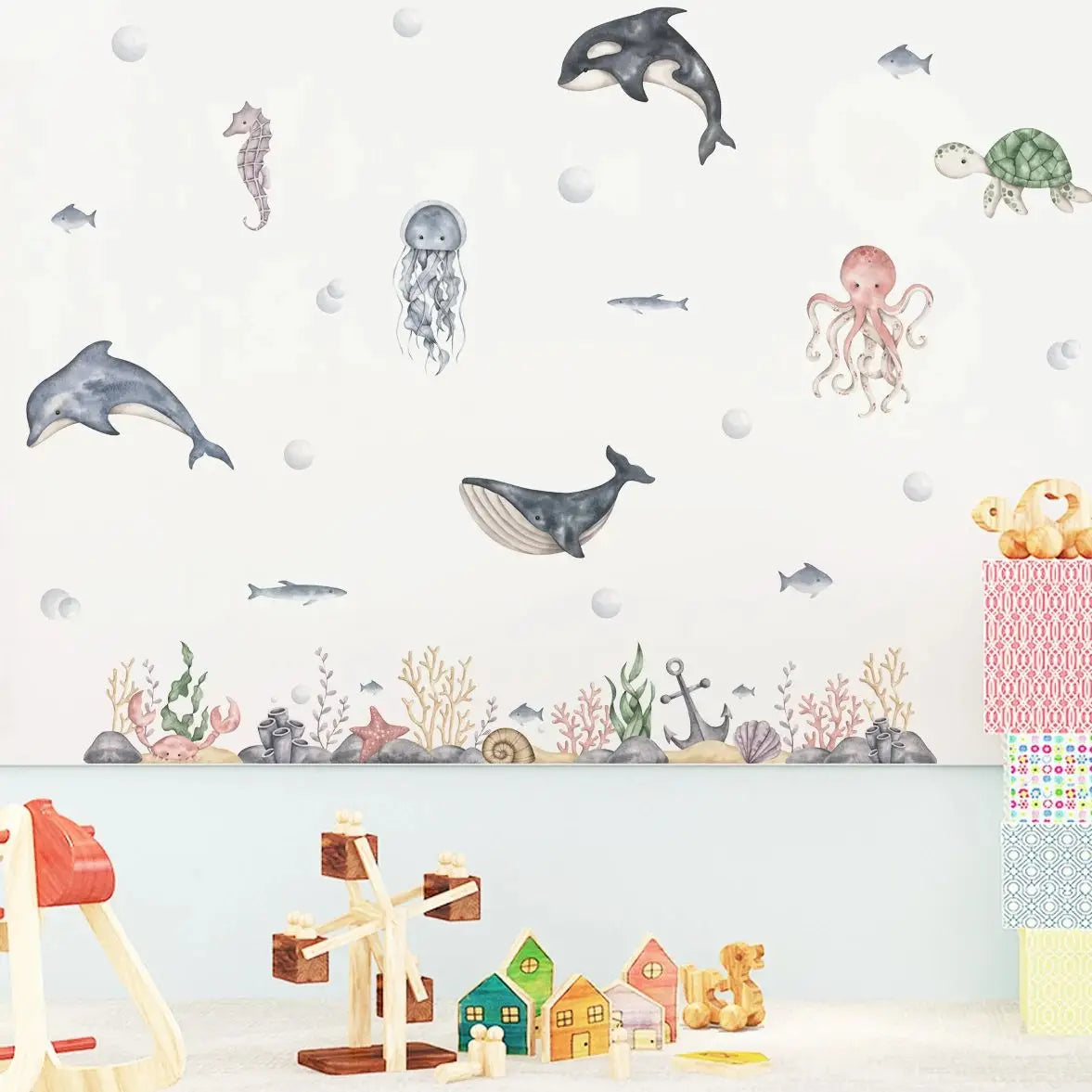 Wallpaper with ocean-themed stickers on a wall with toys below.