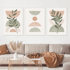 Three abstract art prints in a living room setting with a beige sofa and decorative items.