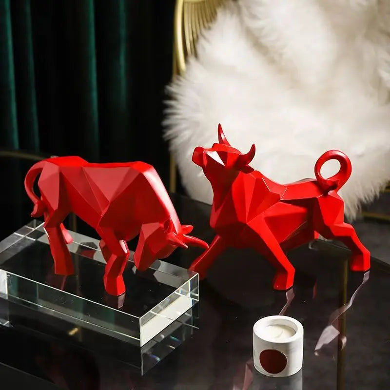 Two red bull figurines on a reflective surface with a blurred background