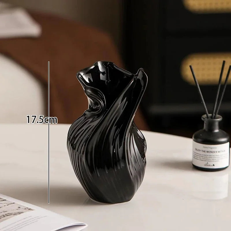 Black decorative vase on a table with a diffuser bottle in the background