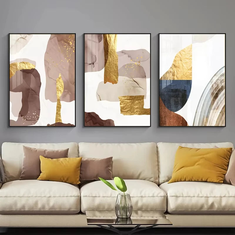 Three abstract art pieces on a wall above a beige sofa with colorful cushions.