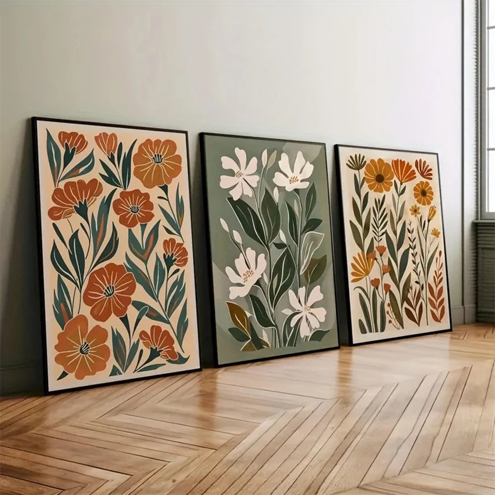 Three floral art prints on a wall in a room with wooden flooring.