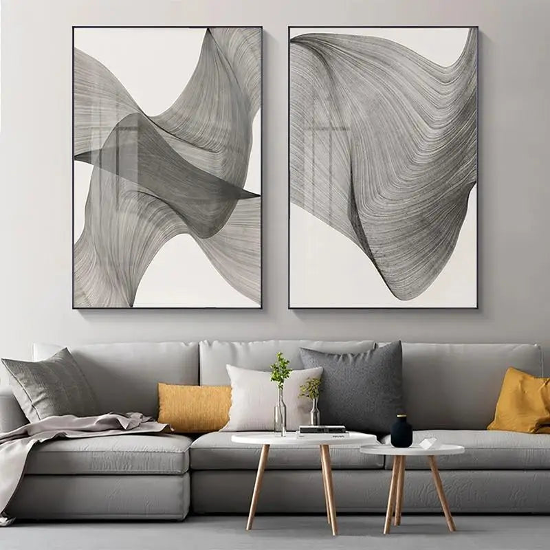 Two abstract art pieces on a wall above a gray sofa with colorful cushions.