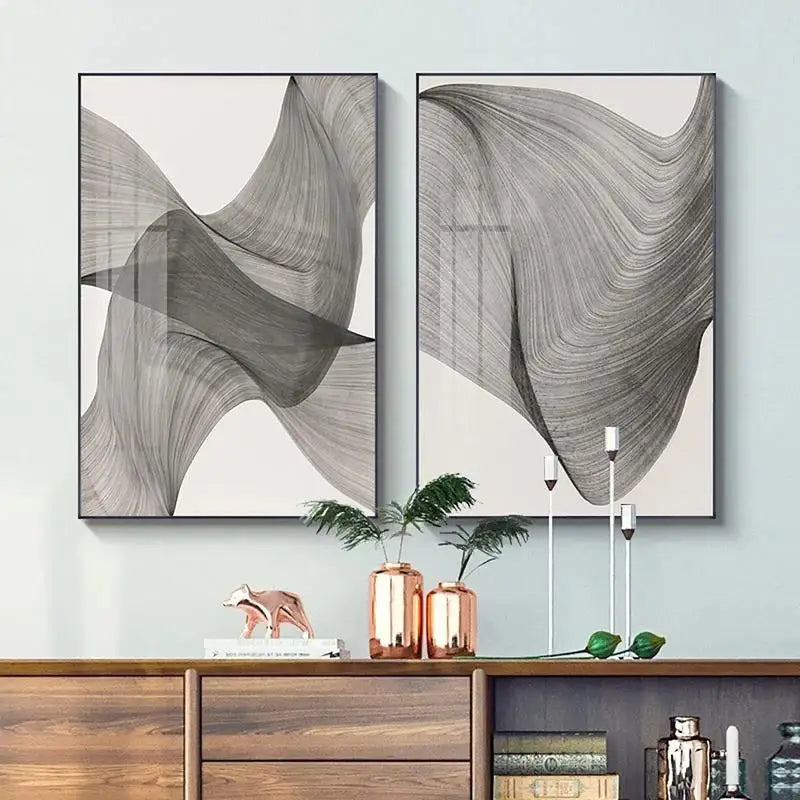 Two abstract wall art pieces on a light gray wall above a wooden cabinet.