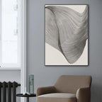 Abstract wall art on a gray wall with a brown armchair and window in the background