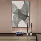 Abstract art piece on a wall above a console table with decorative items.