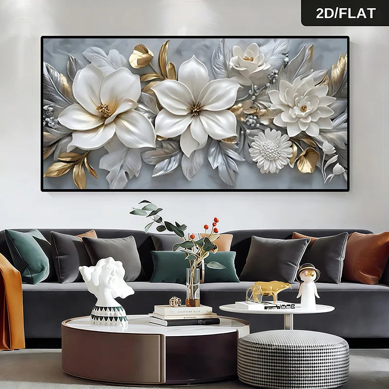A large rectangular wall art piece featuring oversized white and silver flowers with gold accents, displayed above a modern gray sofa in a styled living room. 