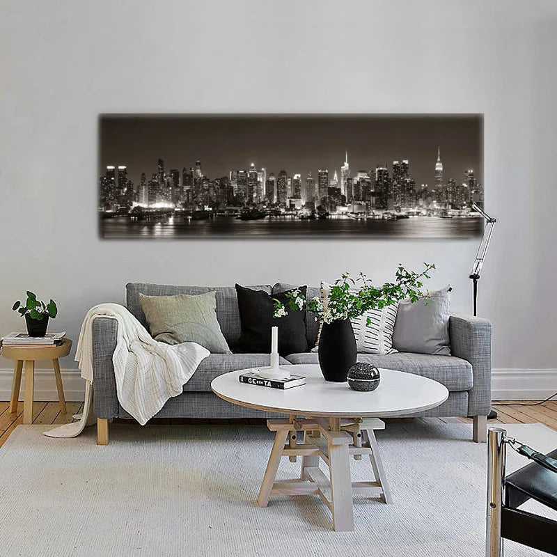 Living room with a gray sofa, round coffee table, and cityscape artwork on the wall.