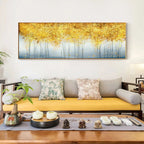 Decorative painting of a golden forest above a sofa with decorative items on a table.