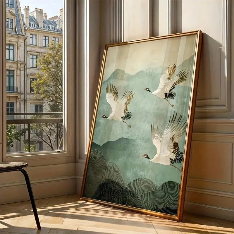 Framed artwork of cranes flying over water in a room with large windows.
