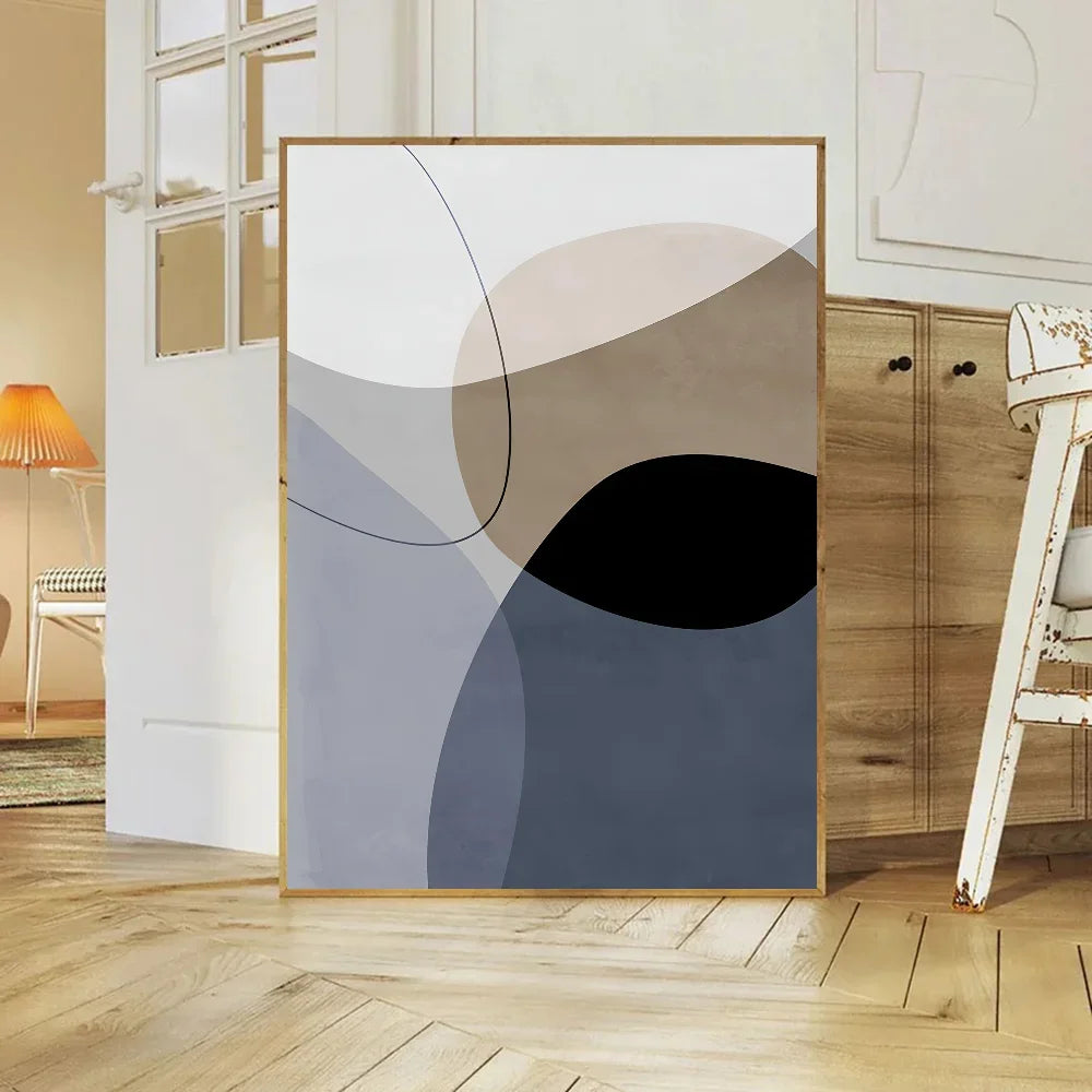 Abstract art print in a gold frame on a wall in a room with wooden flooring and furniture.