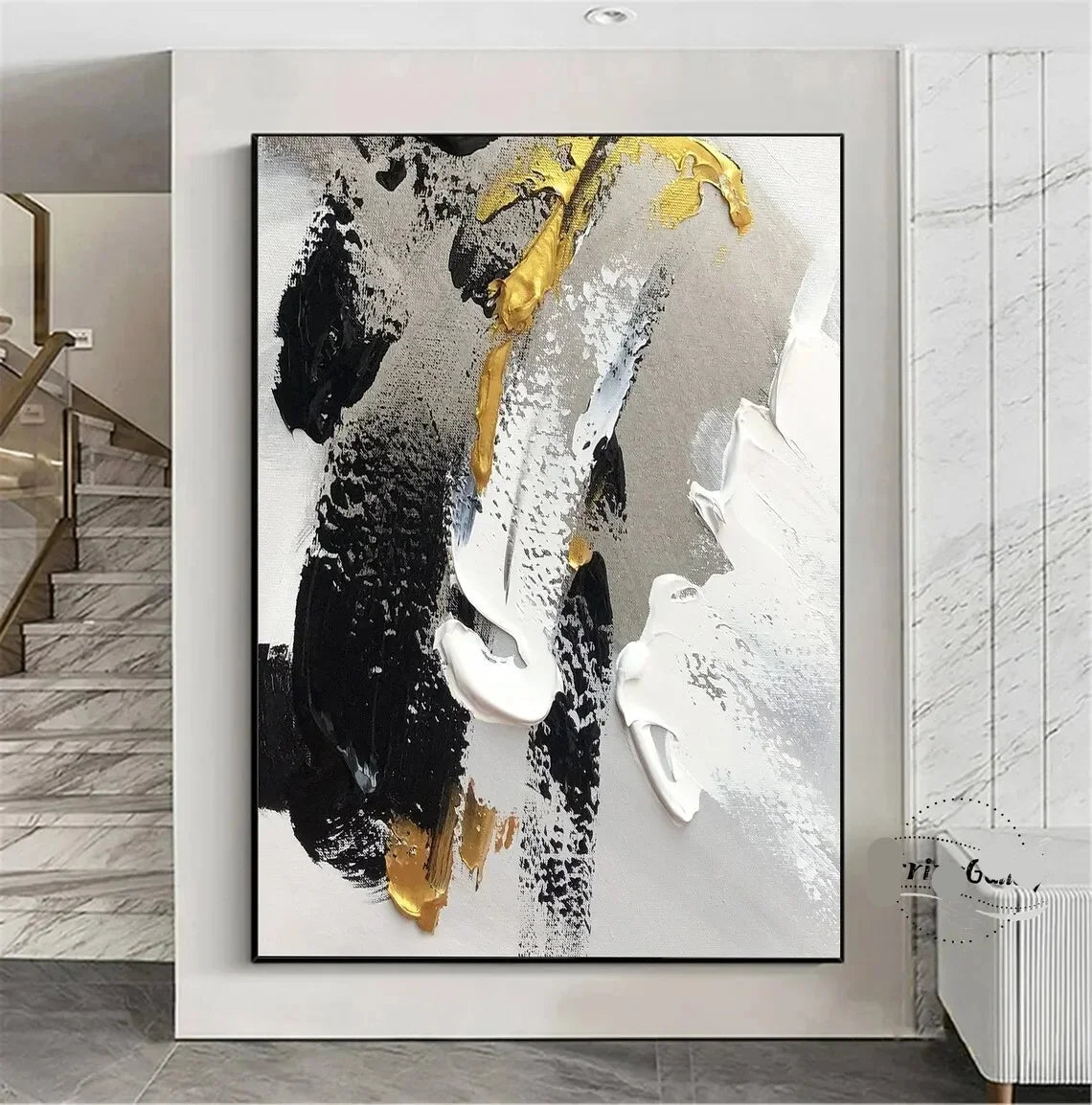 Abstract art painting with black, white, and gold on a wall in a modern interior setting.