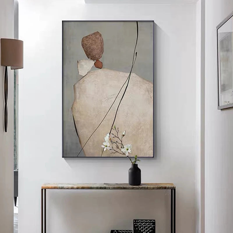 Abstract art piece on a wall with a vase of flowers on a table below.