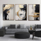 Three abstract art pieces in a living room setting with a gray sofa and black ottoman.