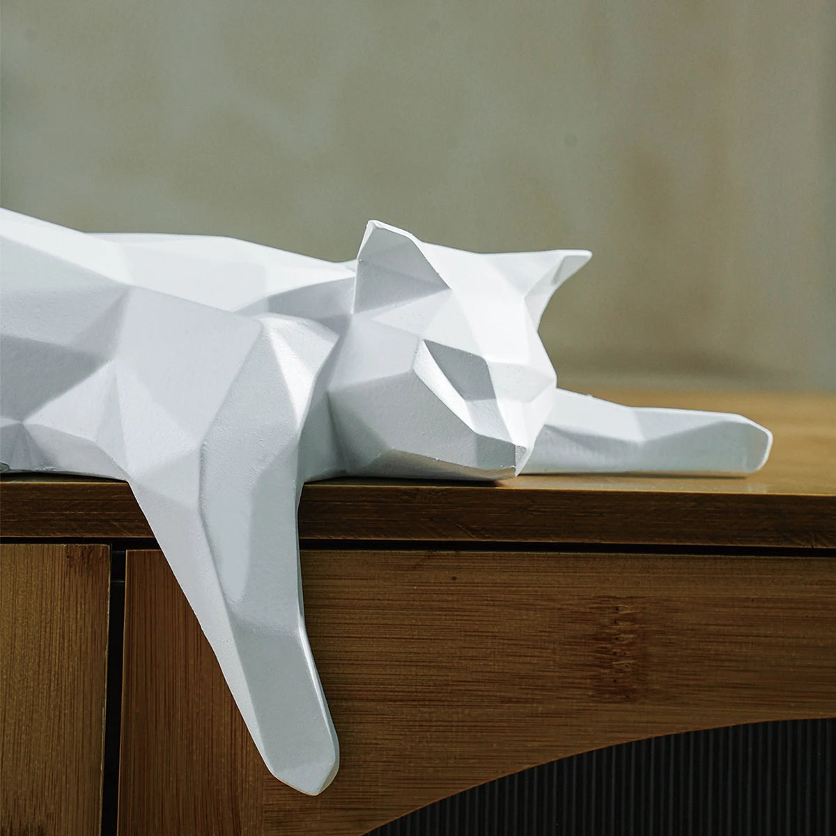 White geometric cat sculpture on a wooden surface with a neutral background