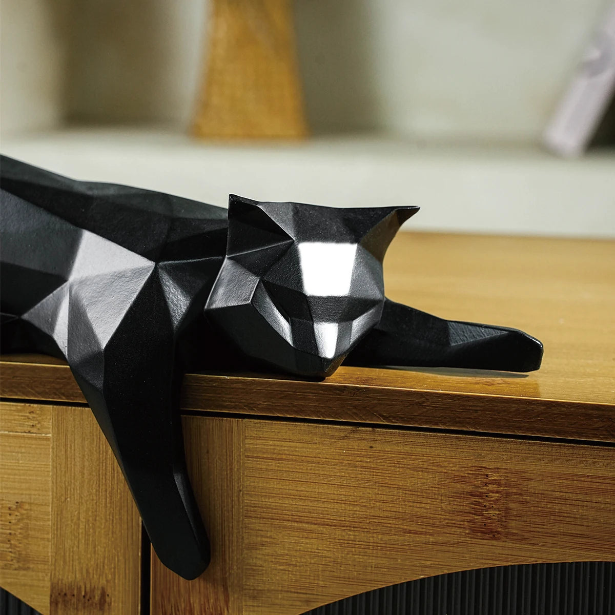 Black geometric cat sculpture on a wooden surface