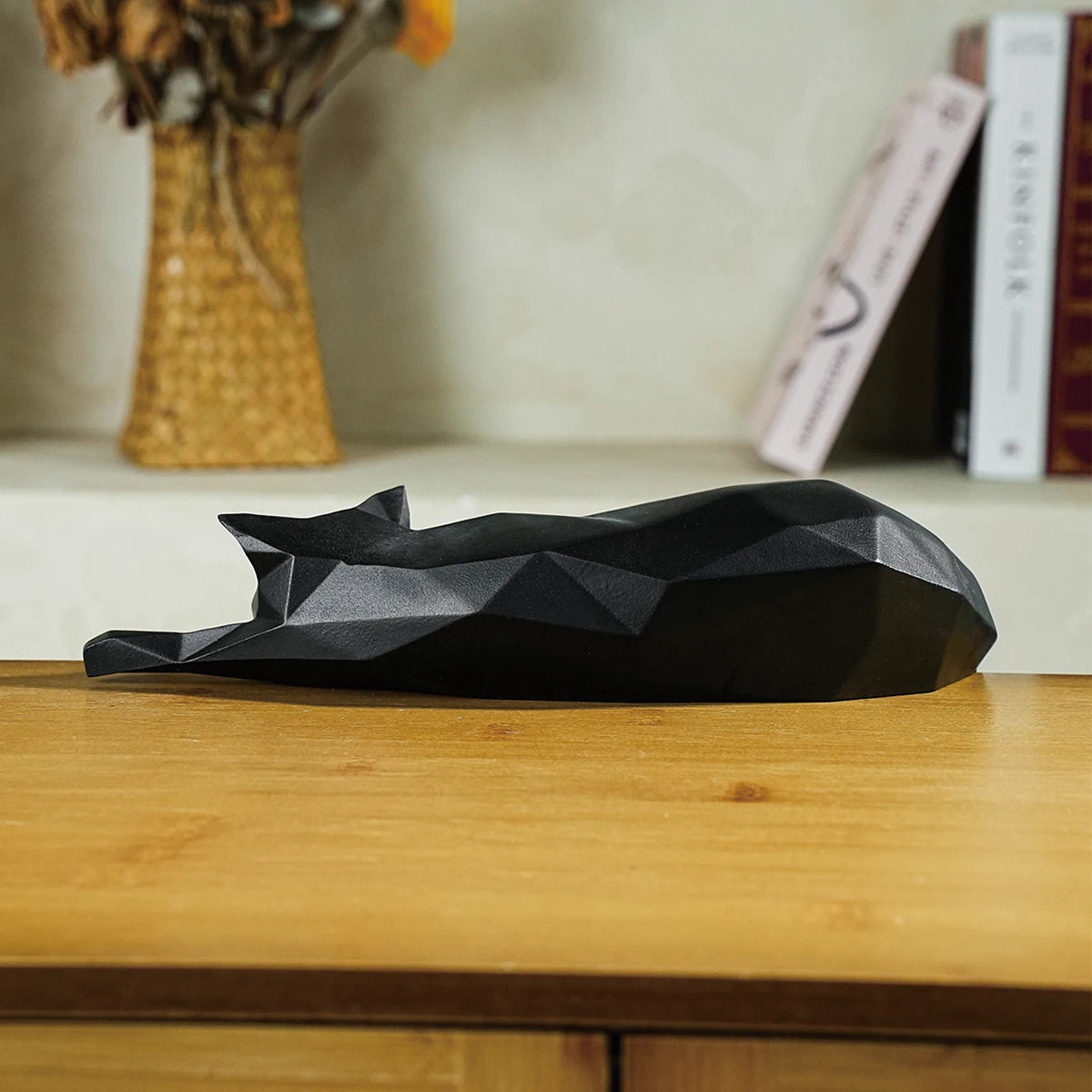 Black geometric cat sculpture on a wooden surface with a blurred background