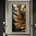 A vertical canvas wall art piece featuring a large textured gold feather on a black background, displayed in a modern hallway setting.