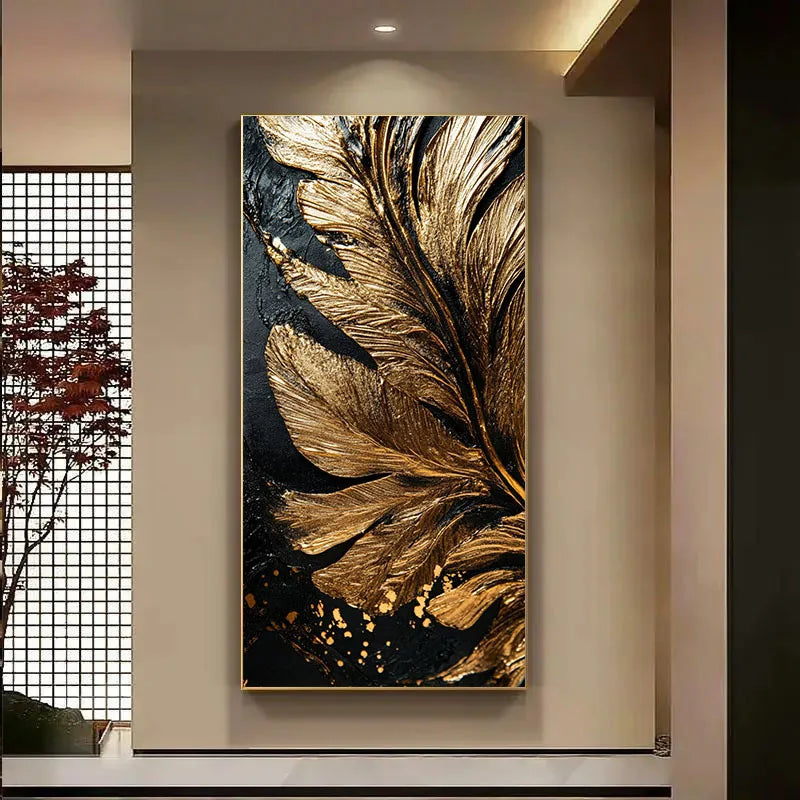 A vertical wall art piece featuring a large metallic gold feather motif on a black background, displayed in a modern interior setting with a beige wall and a window screen to the left.