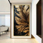 A vertical wall art piece featuring an abstract large feather design in metallic gold over a black background, displayed in a modern interior hallway.