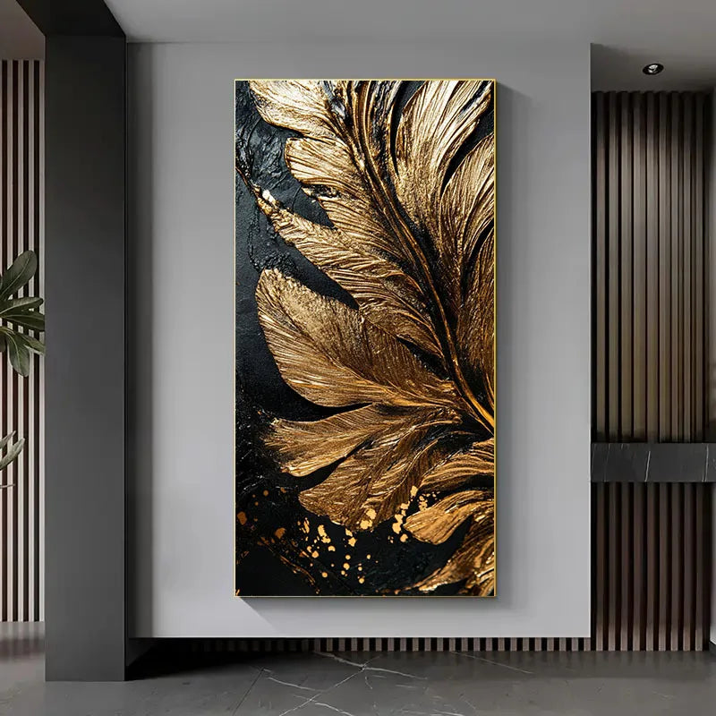 A vertical wall art piece featuring large metallic gold feather-like leaves on a black background, displayed in a modern interior with gray walls and dark wood slat accents.