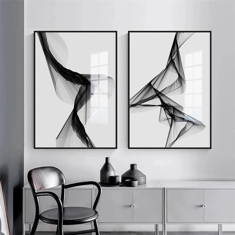 Two abstract black and white artworks on a wall with a chair and cabinet below.