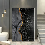 A large vertical wall art print displayed in a modern interior. The artwork features a black and gray wood grain tree-ring pattern on the left, transitioning into a black field covered in white glitter-like speckles on the right, with a wavy metallic gold border separating the two sections.