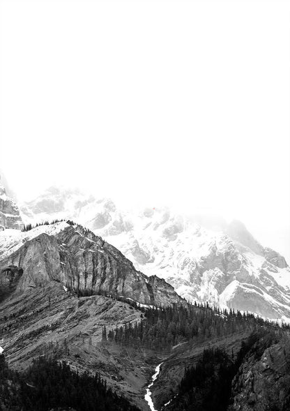Black and white photograph of a mountain landscape with snow-capped peaks and forested valleys.