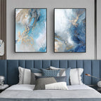 Two abstract art pieces on a wall above a bed with decorative pillows.