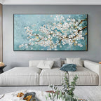 Framed artwork of cherry blossoms on a wall above a sofa in a living room.