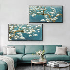Two framed paintings of floral branches on a wall above a teal sofa.