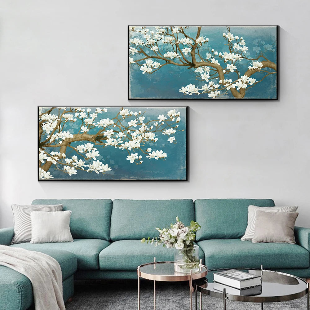 Two framed paintings of floral branches on a wall above a teal sofa.