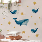 Wall with whale and star decals, pillows on a bed, and plants.