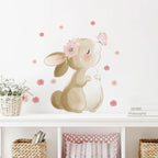 Wall decal of a bunny with flowers on a white wall above a shelf with decorative items.