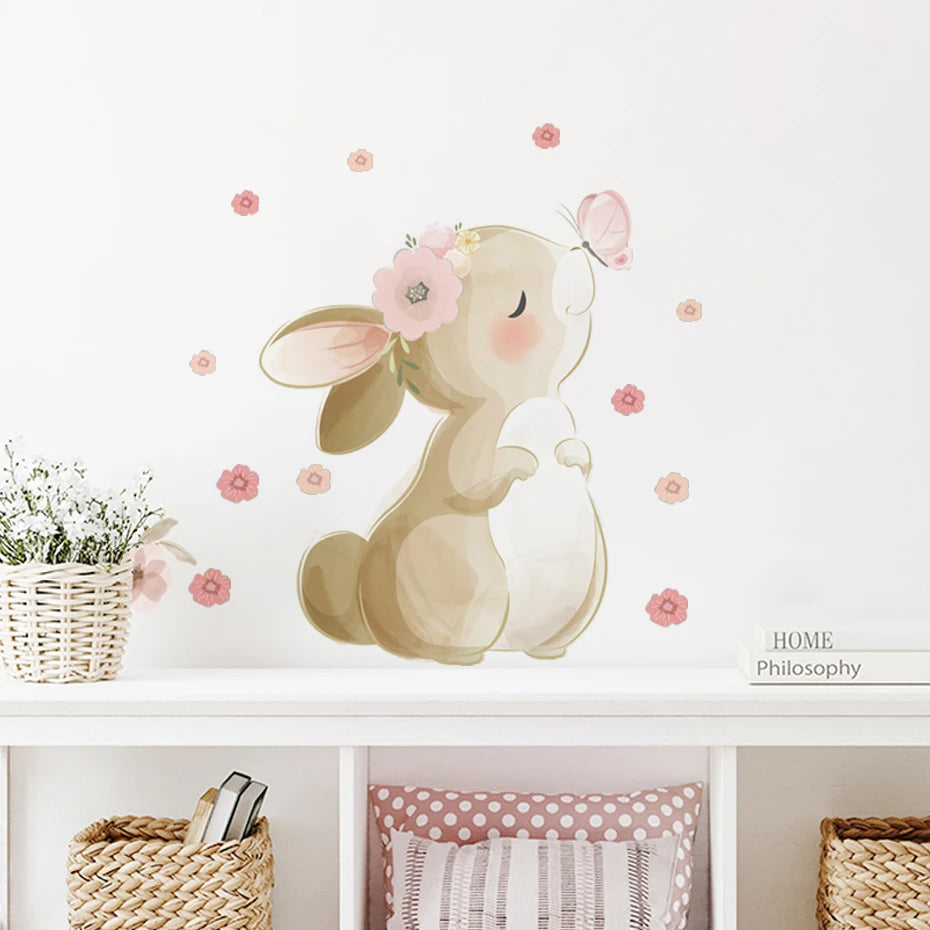 Wall decal of a bunny with flowers on a white wall above a shelf with decorative items.