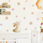 Children's room with a decorative wall sticker of a rabbit with flowers, floral decals on the wall, and shelves with books and toys.