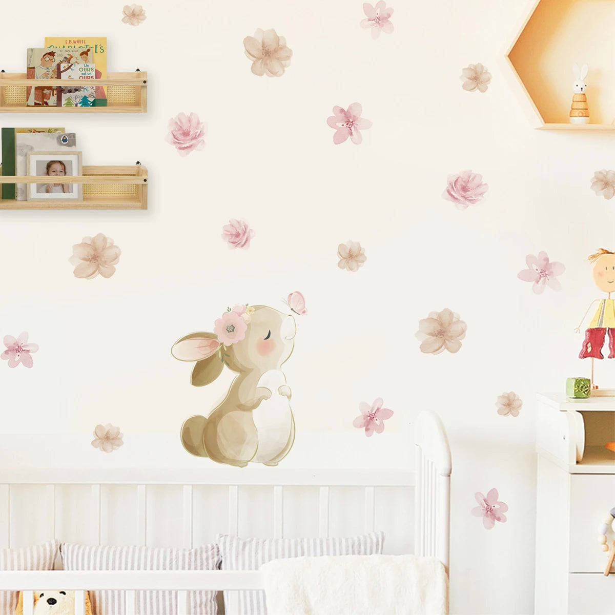 Children's room with a decorative wall sticker of a rabbit with flowers, floral decals on the wall, and shelves with books and toys.