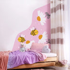 Children's room with a bed featuring cartoon bees and flowers on a pink wall.