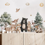Wooden toys of animals on a wooden shelf with a forest-themed wallpaper.