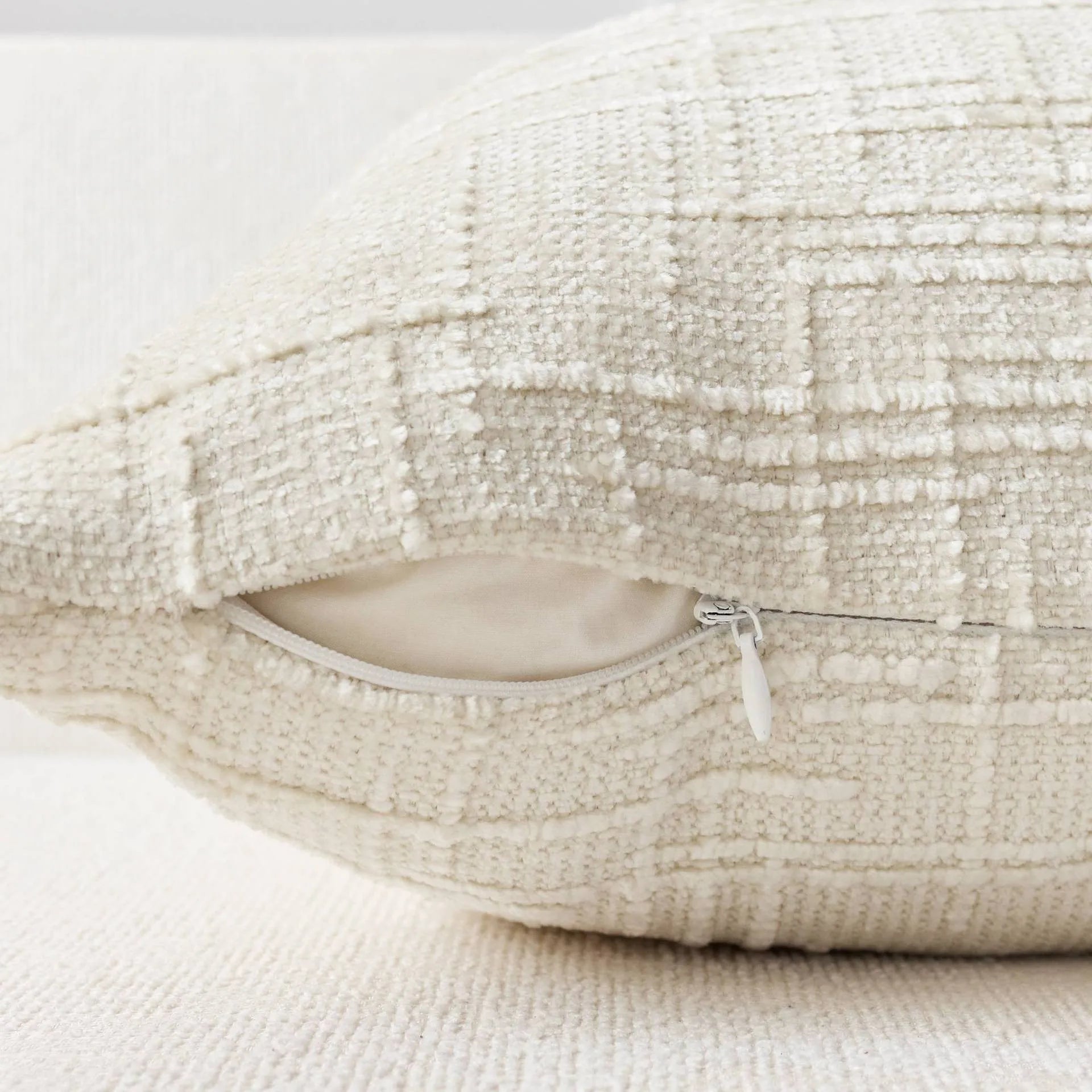 Textured beige pillow with a zipper on a light background