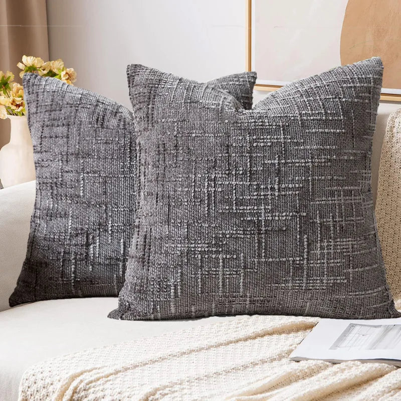 Two gray textured throw pillows on a sofa with a neutral background
