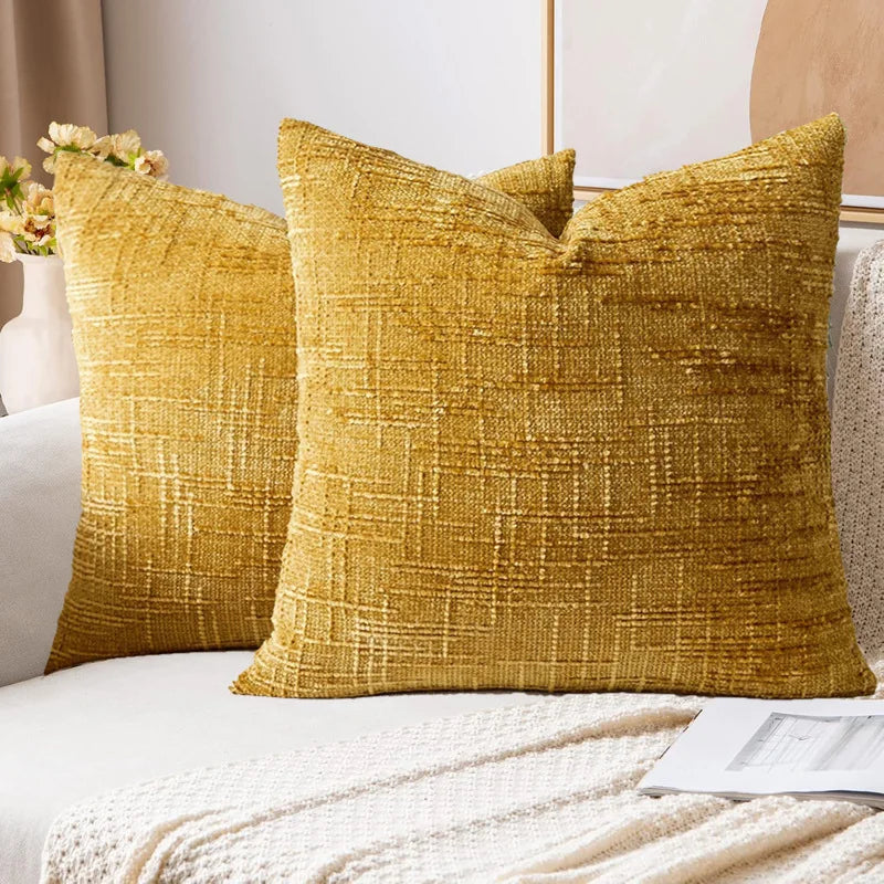 Two gold textured pillows on a sofa with a neutral background