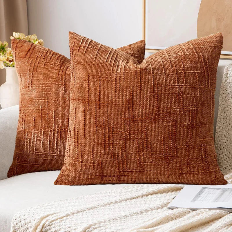 Two brown textured pillows on a white sofa with a neutral background